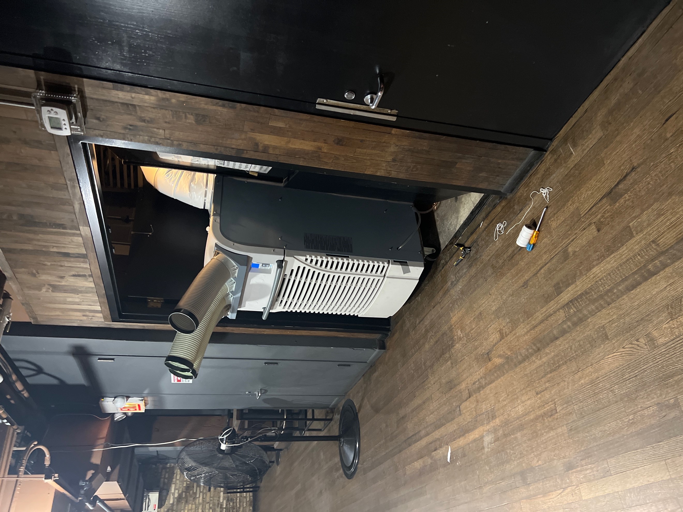 5-ton portable air-cooled unit straddling elevator door opening with cold air chutes pointed into the bar area.