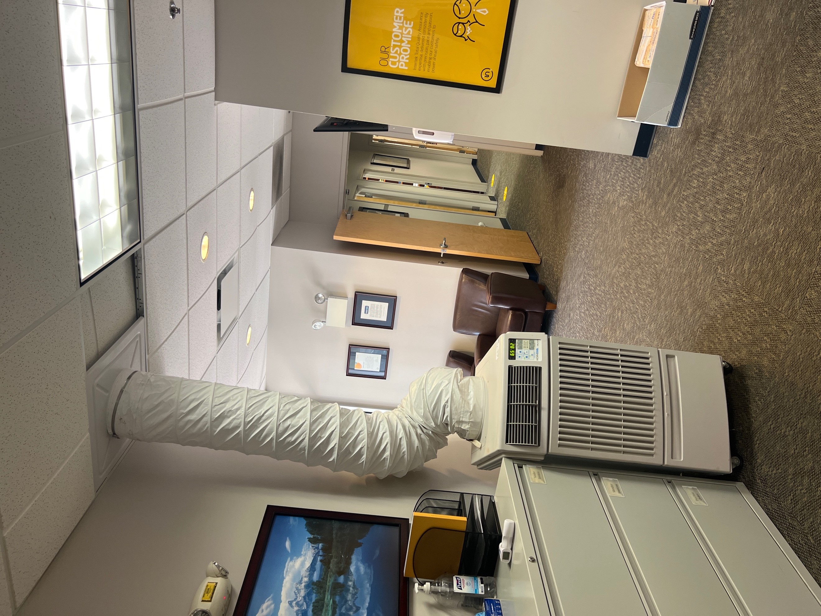 A 1-ton portable spot cooler blowing cool air towards employees in an office setting.  