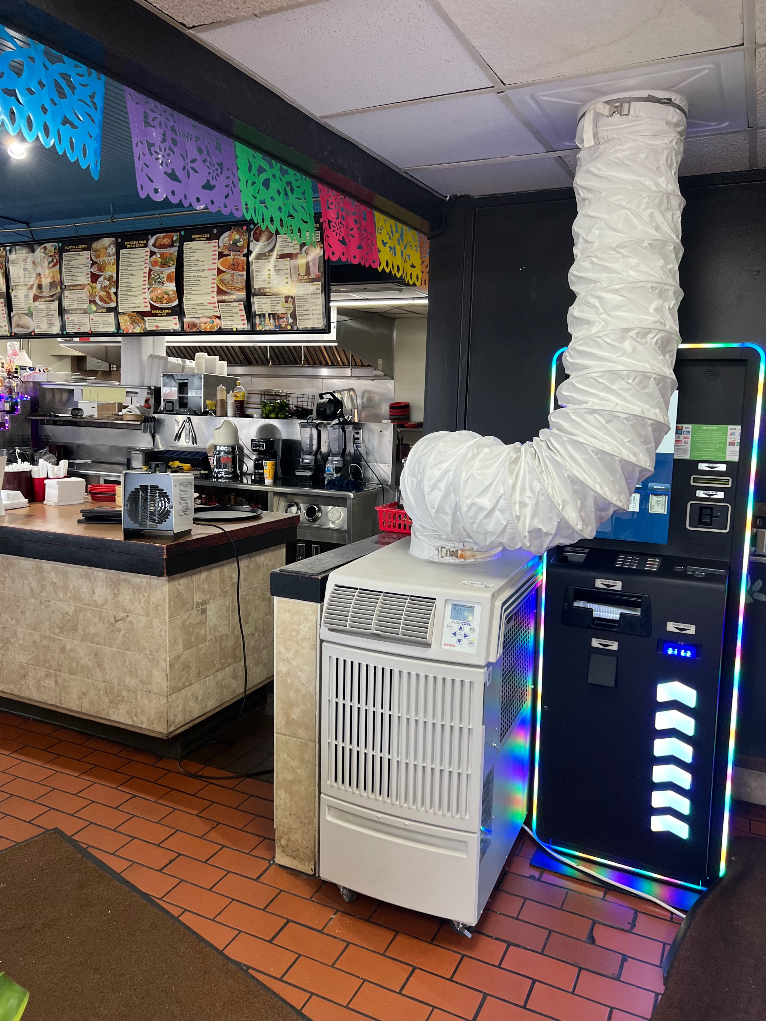 A Climate Pro Heat Pump rental on wheels placed in a fast-food restaurant floor with a 1.5 kW electric heater positioned on the service counter. 